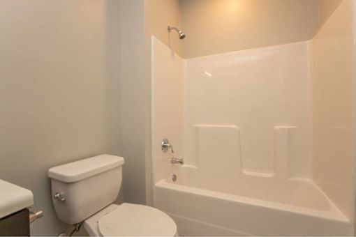 A white toilet sits next to a white bathtub in a bathroom.