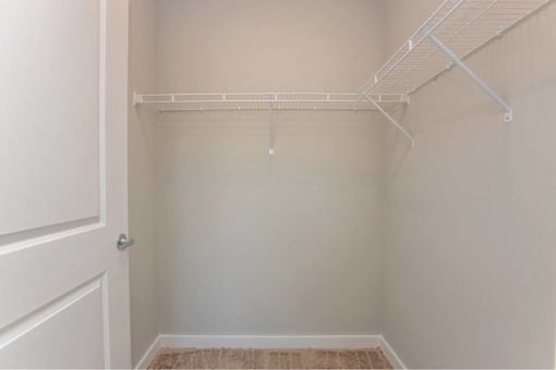 A white closet with a white door and a white shelf.