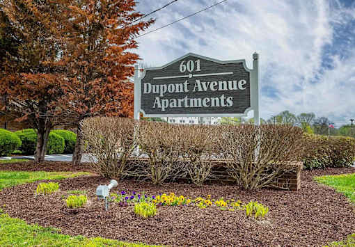 A sign for Dupont Avenue Apartments is displayed in front of a landscaped area.