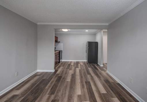 A room with wooden flooring and a black refrigerator.