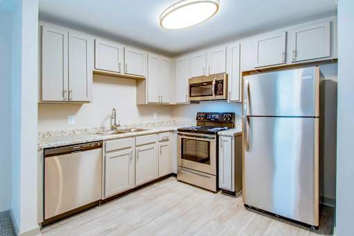A kitchen with a refrigerator, oven, and sink.