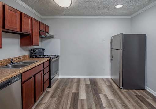 A kitchen with a black fridge and brown cabinets.
