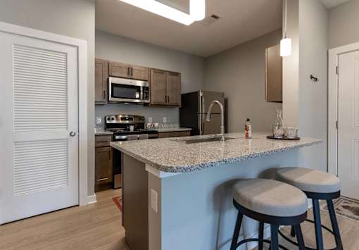 A kitchen with a white door and a counter with two stools.