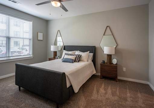 A bedroom with a bed, two lamps, and a ceiling fan.