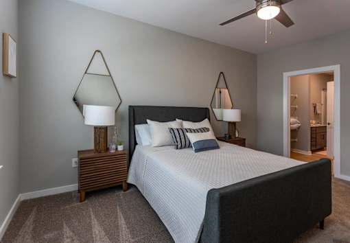 A bedroom with a bed, two lamps, and a ceiling fan.