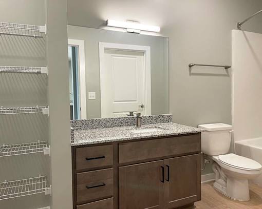 A bathroom with a sink, toilet, and a mirror.