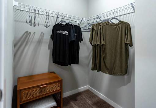 A small closet with a shelf and a bench underneath it.