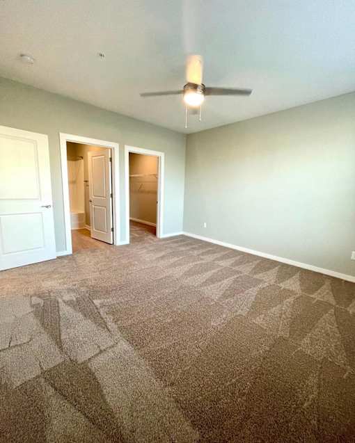 A room with a carpeted floor and a ceiling fan.