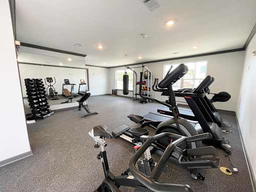 A spacious gym with a variety of equipment including treadmills, stationary bikes, and weight machines.