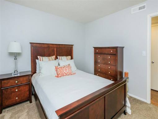 A bedroom with a bed, nightstand, and dresser.