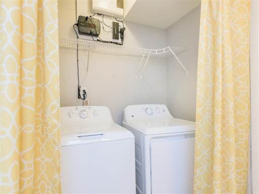 Two white washing machines in a small laundry room.