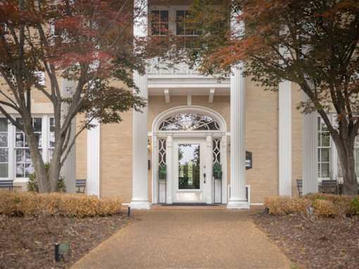 A building with a white arched entrance and a walkway leading to it.