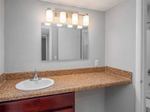 A bathroom sink with a granite countertop and a mirror above it.