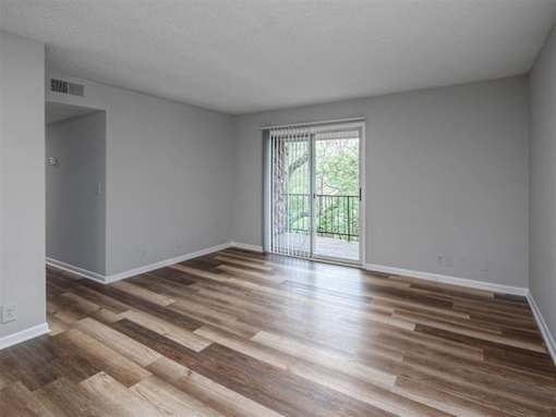 A room with wooden flooring and a sliding glass door.