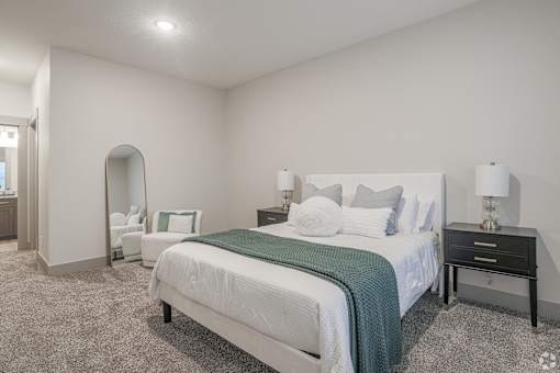 A bedroom with a large bed and a nightstand with a lamp.