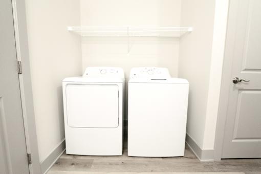 Two white washing machines in a small laundry room.