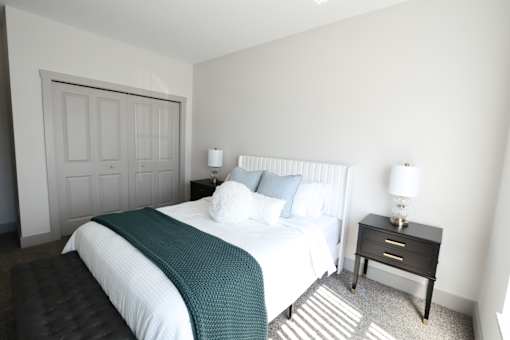 A bedroom with a large bed and a small bedside table.