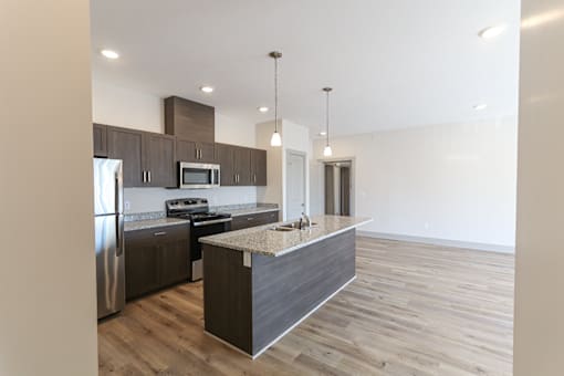 A modern kitchen with stainless steel appliances and wooden flooring.
