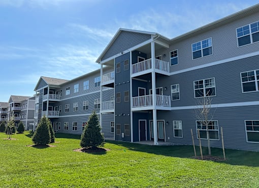 A large grey building with a balcony and a lawn in front.