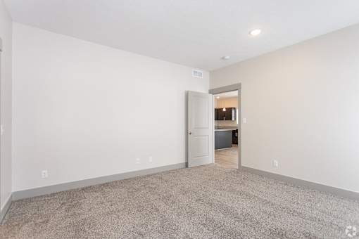 A room with a carpeted floor and a doorway leading to another room.
