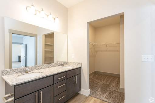 A bathroom with a sink, mirror, and cabinets.