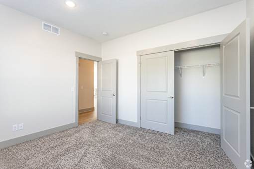 A room with a carpeted floor and three doors.