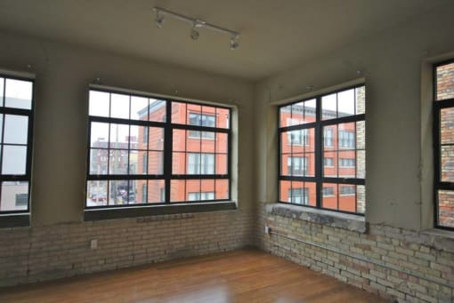 an empty room with large windows and a brick wall
