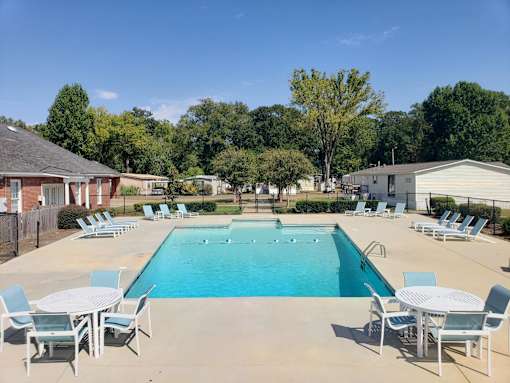 A large swimming pool surrounded by chairs and tables.