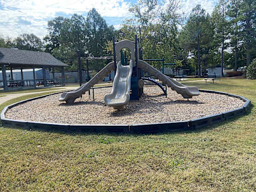 A playground with a slide and a round sandbox.