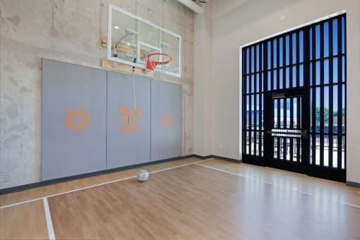 a basketball court in a large room with a door to a gym with a basketball