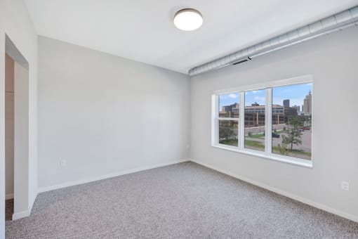 an empty room with a window and a carpeted floor
