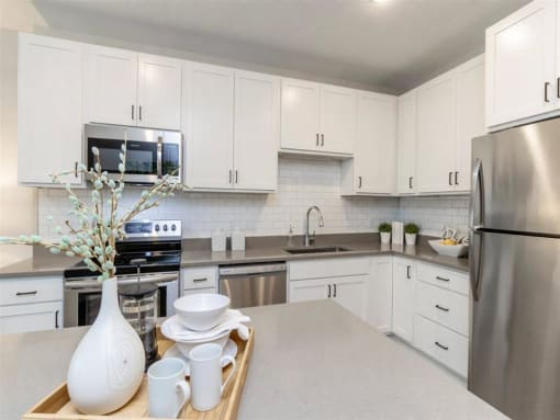 large kitchen with white cabinets, stainless steel appliances and island