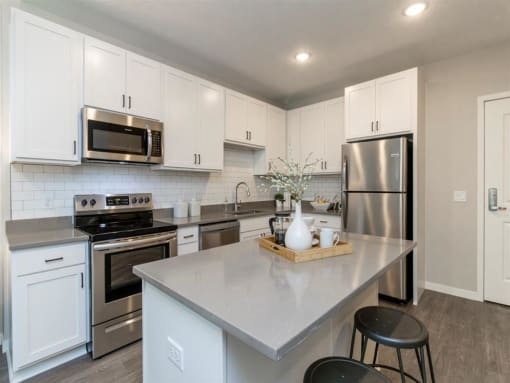 large corner kitchen with white cabinets, stainless steel appliances and island