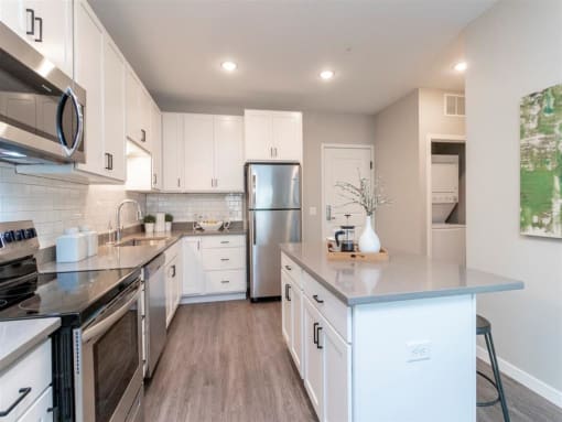 large corner kitchen with white cabinets, stainless steel appliances and island