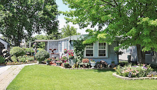 A blue house with a white fence and a garden in front.