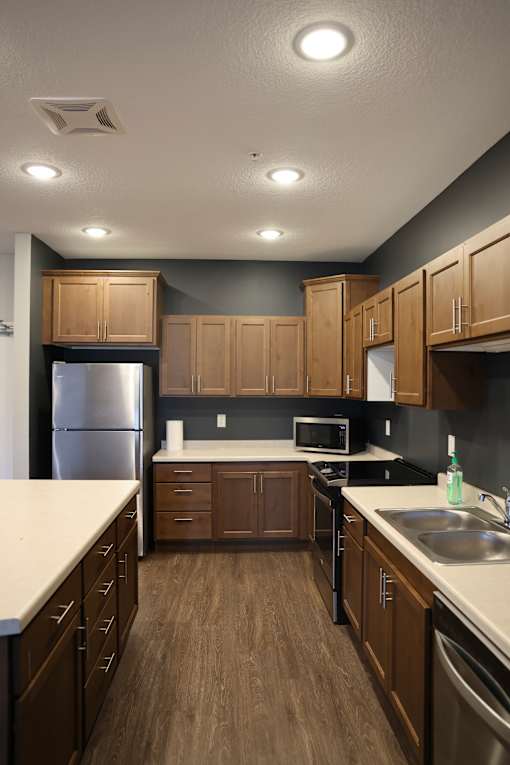 A kitchen with wooden cabinets and a stainless steel refrigerator.