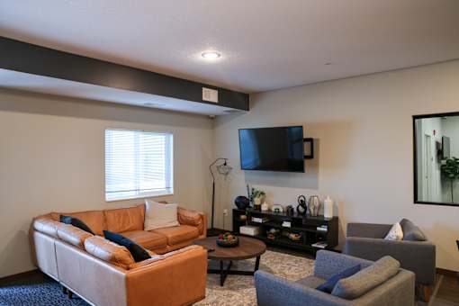 A living room with a brown couch, a grey armchair, and a coffee table.