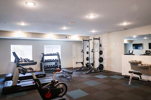 A gym with a variety of equipment including weights and cardio machines.