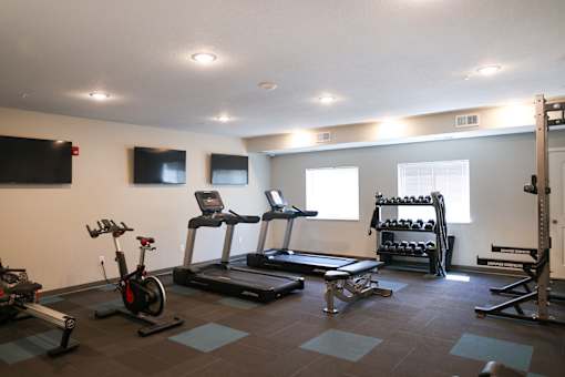 A gym with a variety of equipment including treadmills, stationary bikes, and weight racks.
