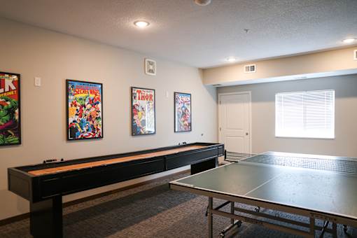 A room with a ping pong table and three comic books on the wall.
