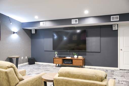 A living room with a large screen tv on the wall.