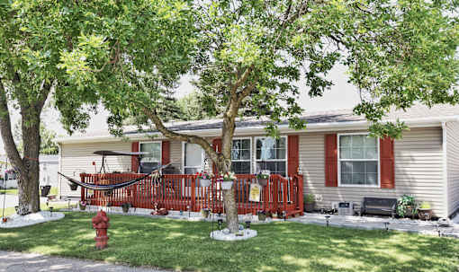 A red house with a hammock on the porch.