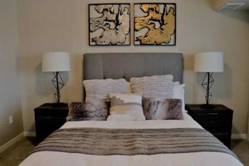 A bedroom with a large bed and two lamps on either side.