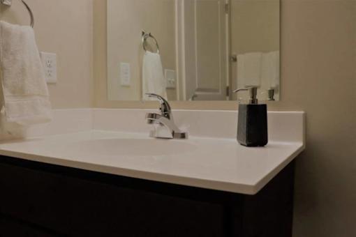 A white sink with a silver faucet and a soap dispenser on a counter.