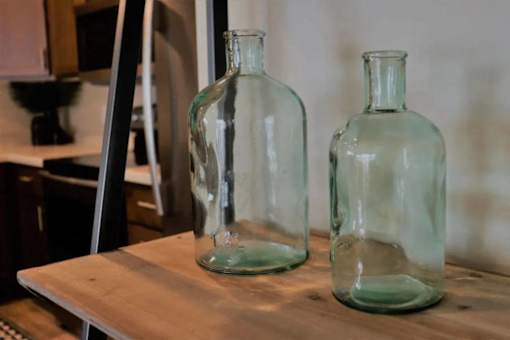 Two green glass bottles on a wooden table.
