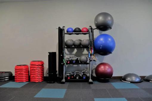A gym with a rack of weights and exercise balls.