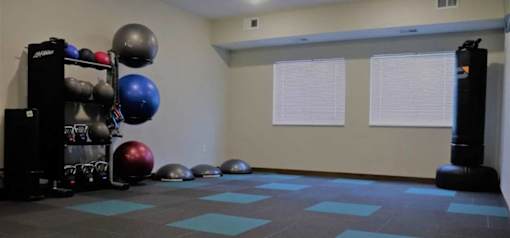 A gym room with a blue mat and a punching bag.