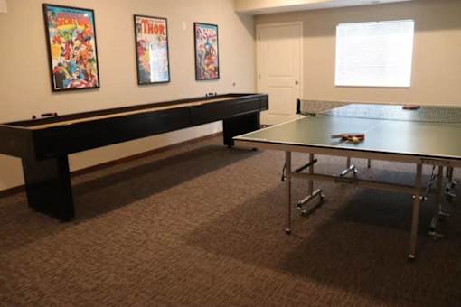 A room with a table tennis table and two posters on the wall.