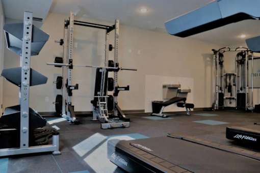 A well equipped gym with a variety of equipment including a squat rack, leg press machine, and a treadmill.