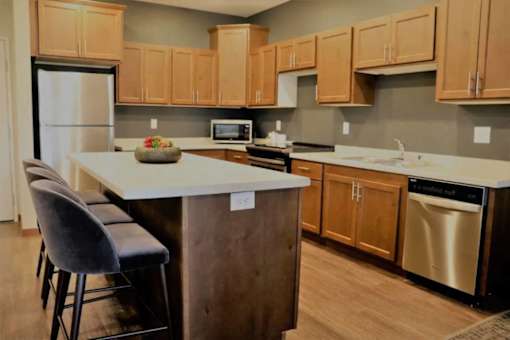 A kitchen with wooden cabinets and a white island.